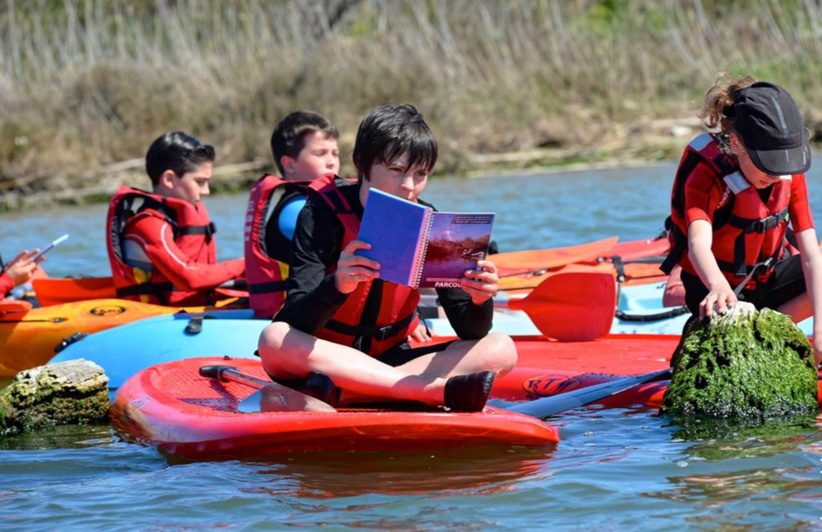 Photo de jeunes assis sur des paddles, sur la rivière